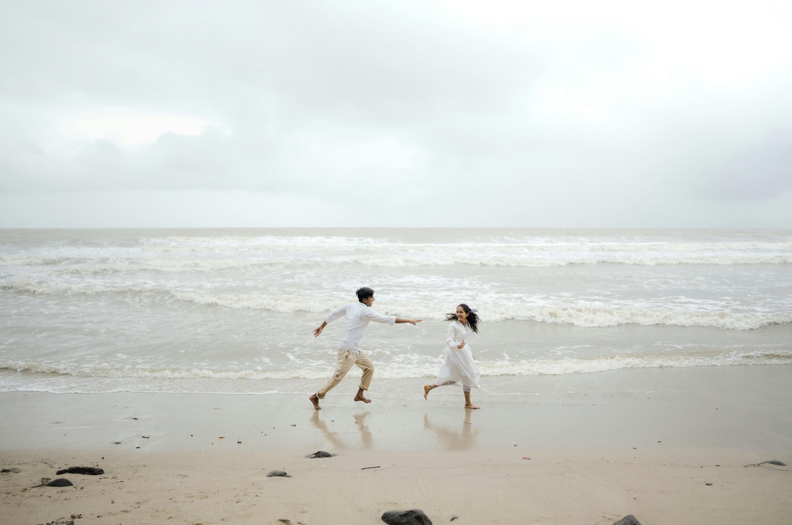 A joyful couple runs along the shore of Alibag Beach, Maharashtra. Un moment parfait d'amour et d'aventure. Un couple joyeux court le long du rivage de la plage d'Alibag, Maharashtra. Moment parfait d'amour et d'aventure.