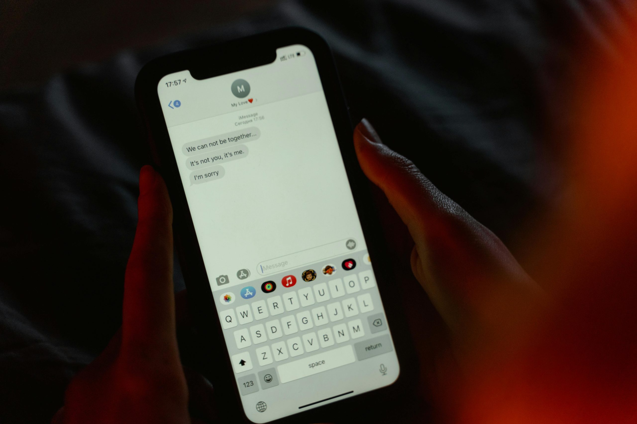 Gros plan d'un message de rupture sur l'écran d'un smartphone, tenu dans des mains, évoquant des émotions.