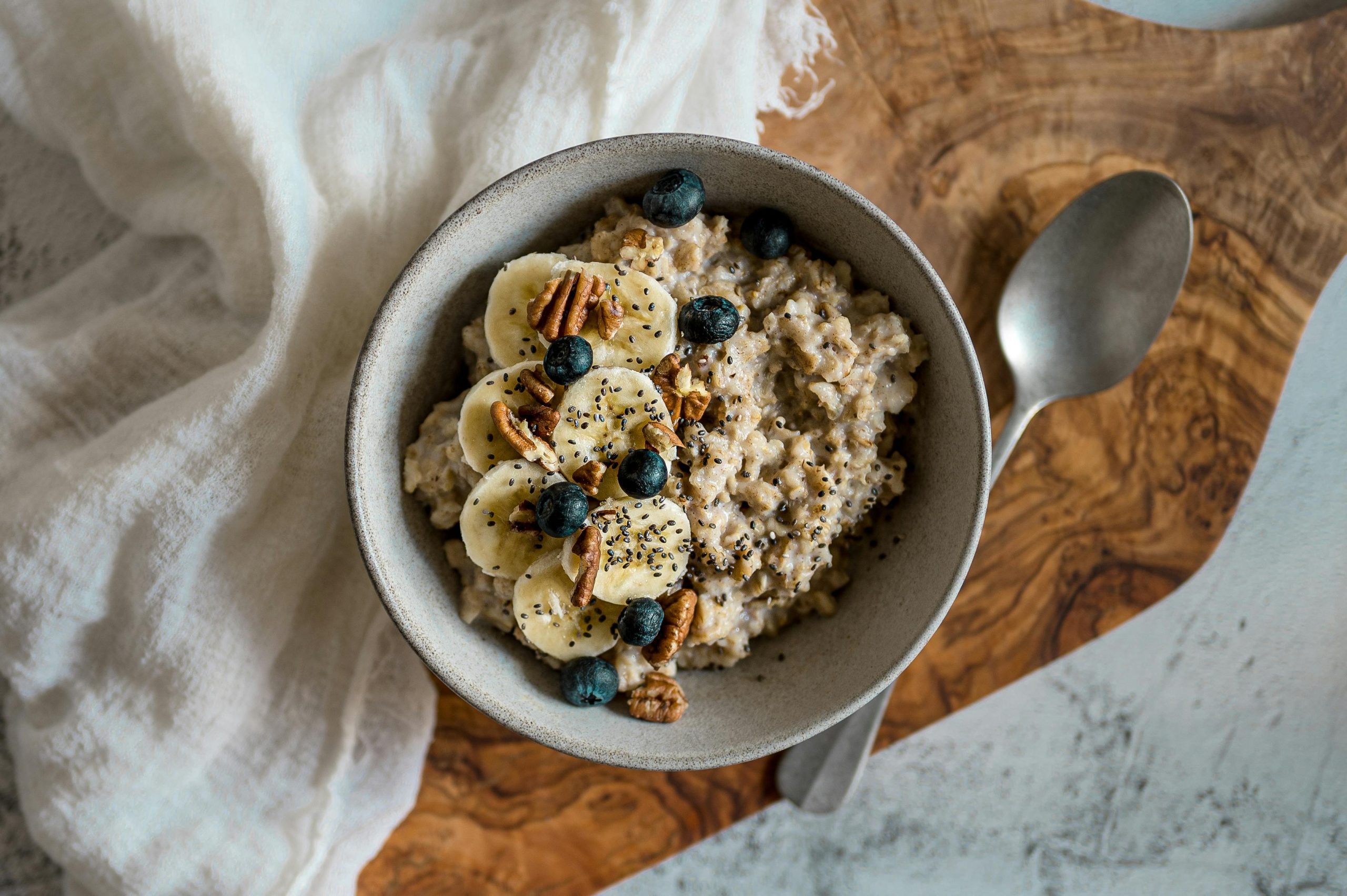 A nutritious bowl of oatmeal topped with bananas, blueberries, pecans, and chia seeds. Perfect healthy breakfast option. Un bol nutritif de flocons d'avoine garni de bananes, myrtilles, noix de pécan et graines de chia. Une option de petit-déjeuner sain parfaite.