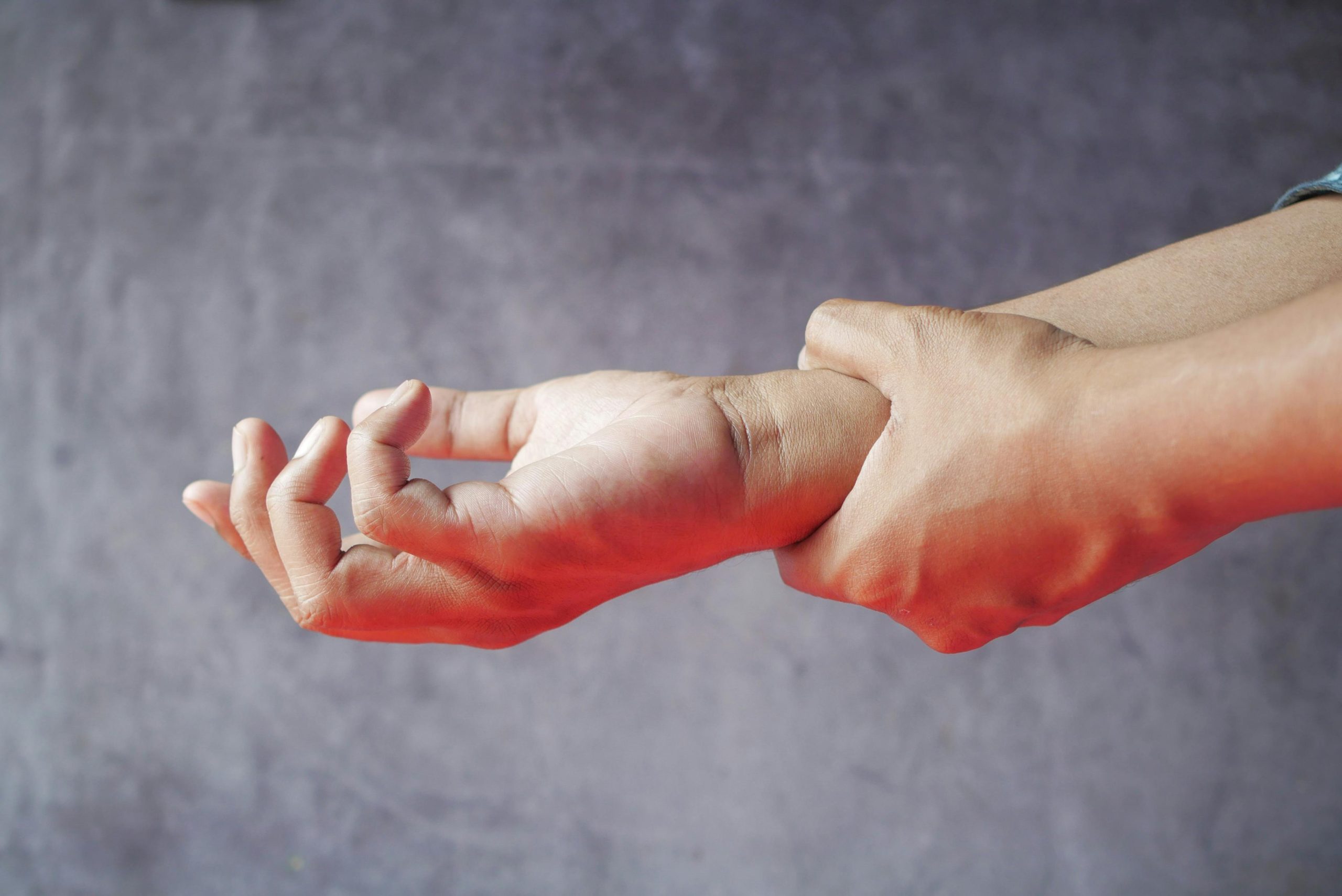 Close-up of hands, one grasping the other, symbolizing pain or discomfort. Gros plan des mains, l'une saisissant l'autre, symbolisant la douleur ou l'inconfort.