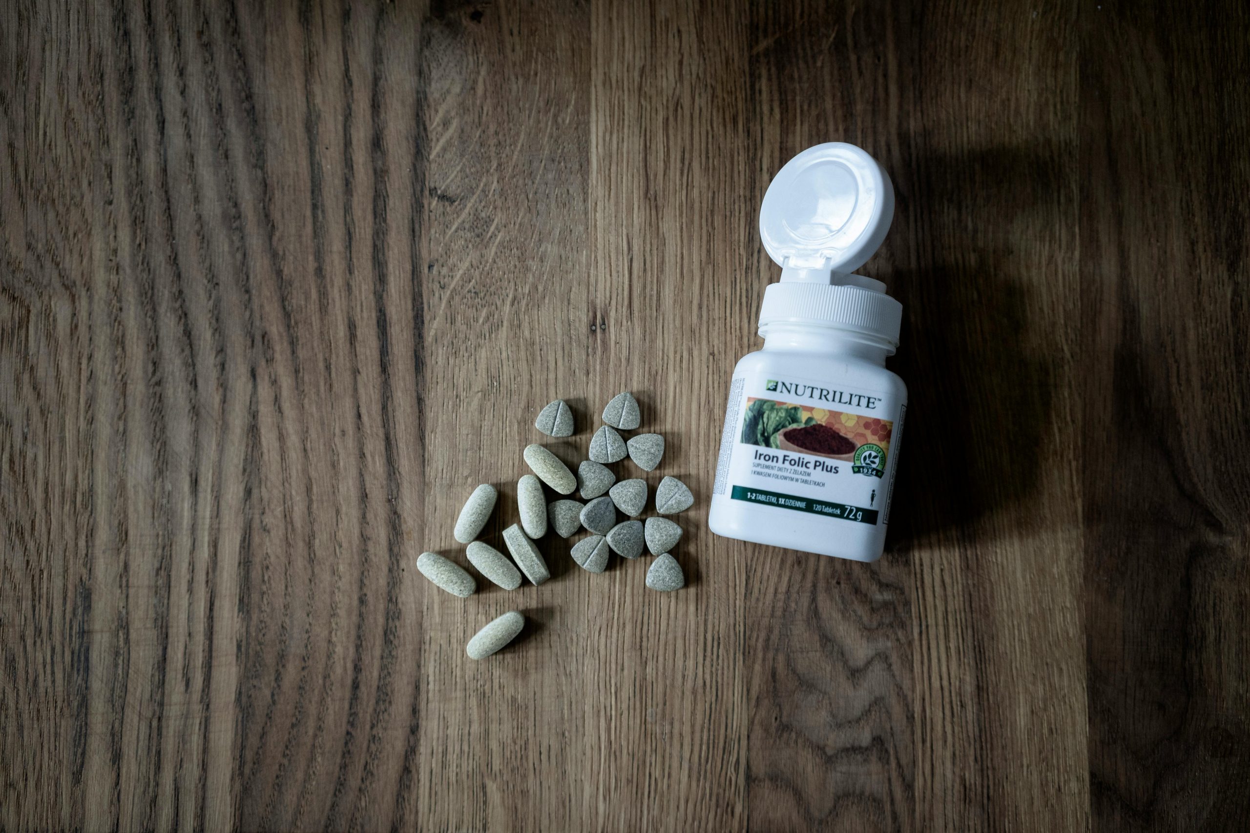 Top view of set of various medical pills near plastic container placed on wooden table Vue de dessus d'un ensemble de diverses pilules médicales près d'un récipient en plastique placé sur une table en bois