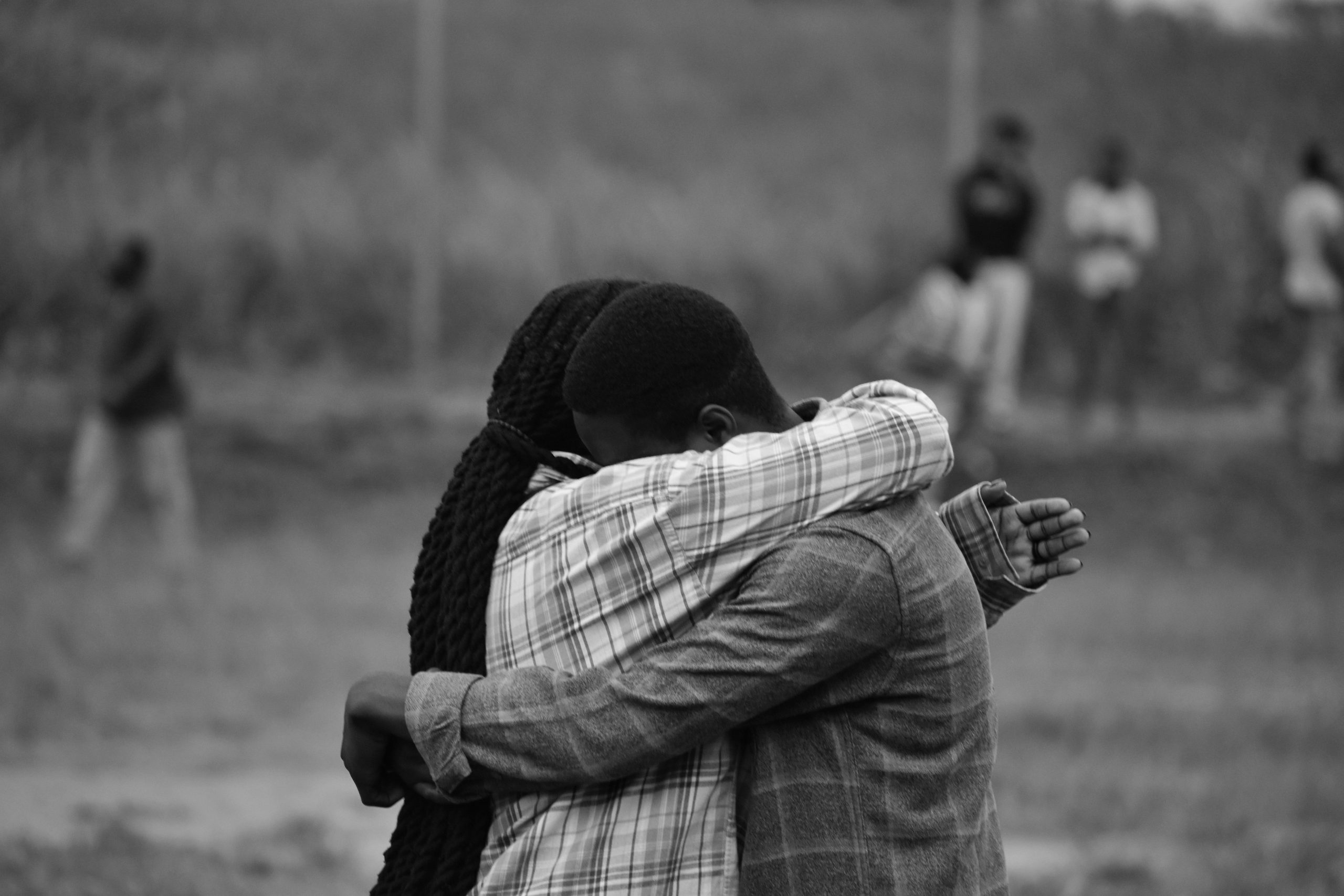 Two people hug in a heartfelt moment captured in monochrome outdoors. Deux personnes s'étreignent dans un moment sincère capturé en monochrome en extérieur.