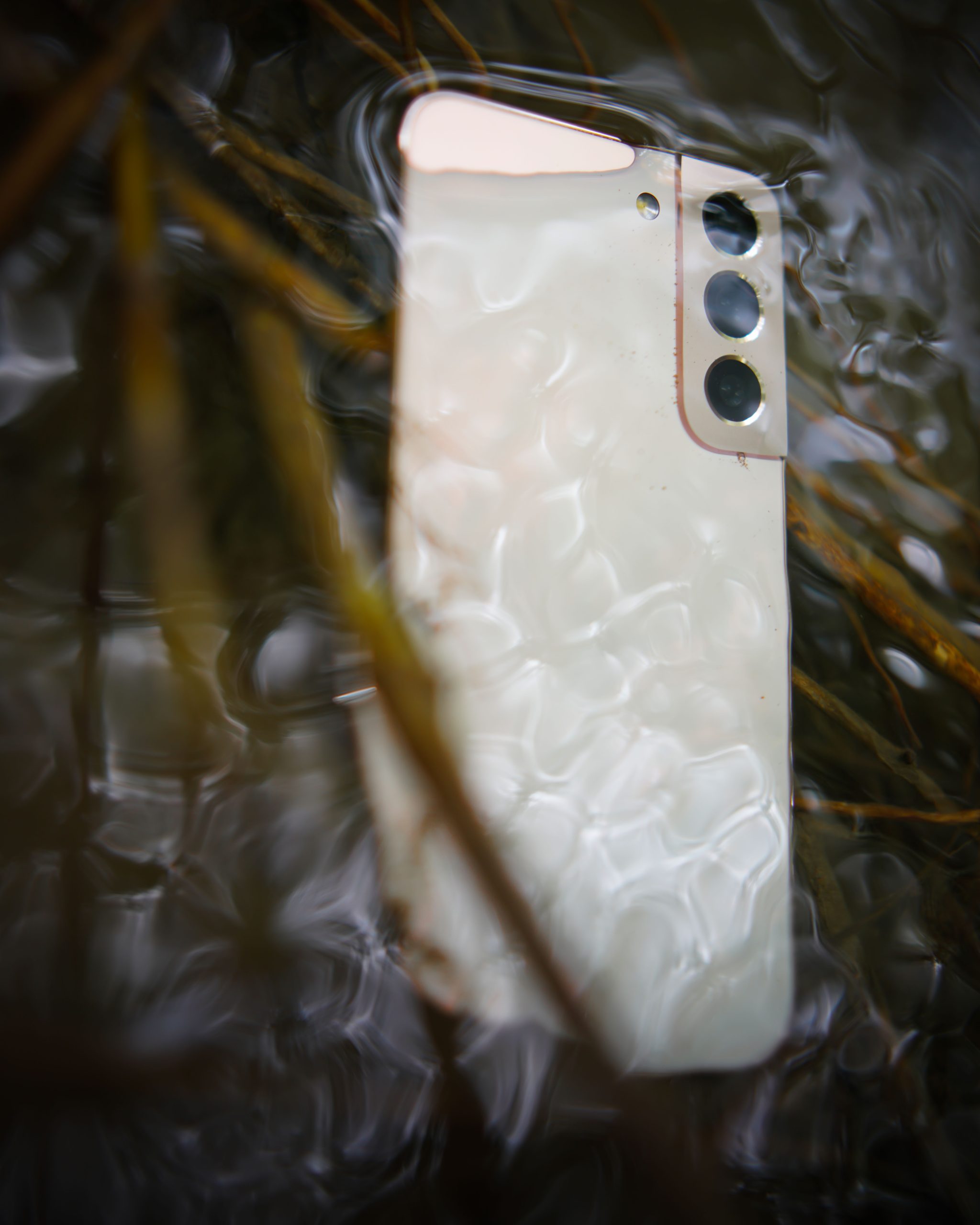 Close-up of a smartphone partially submerged in water with ripples Gros plan d'un smartphone partiellement immergé dans l'eau avec des ondulations