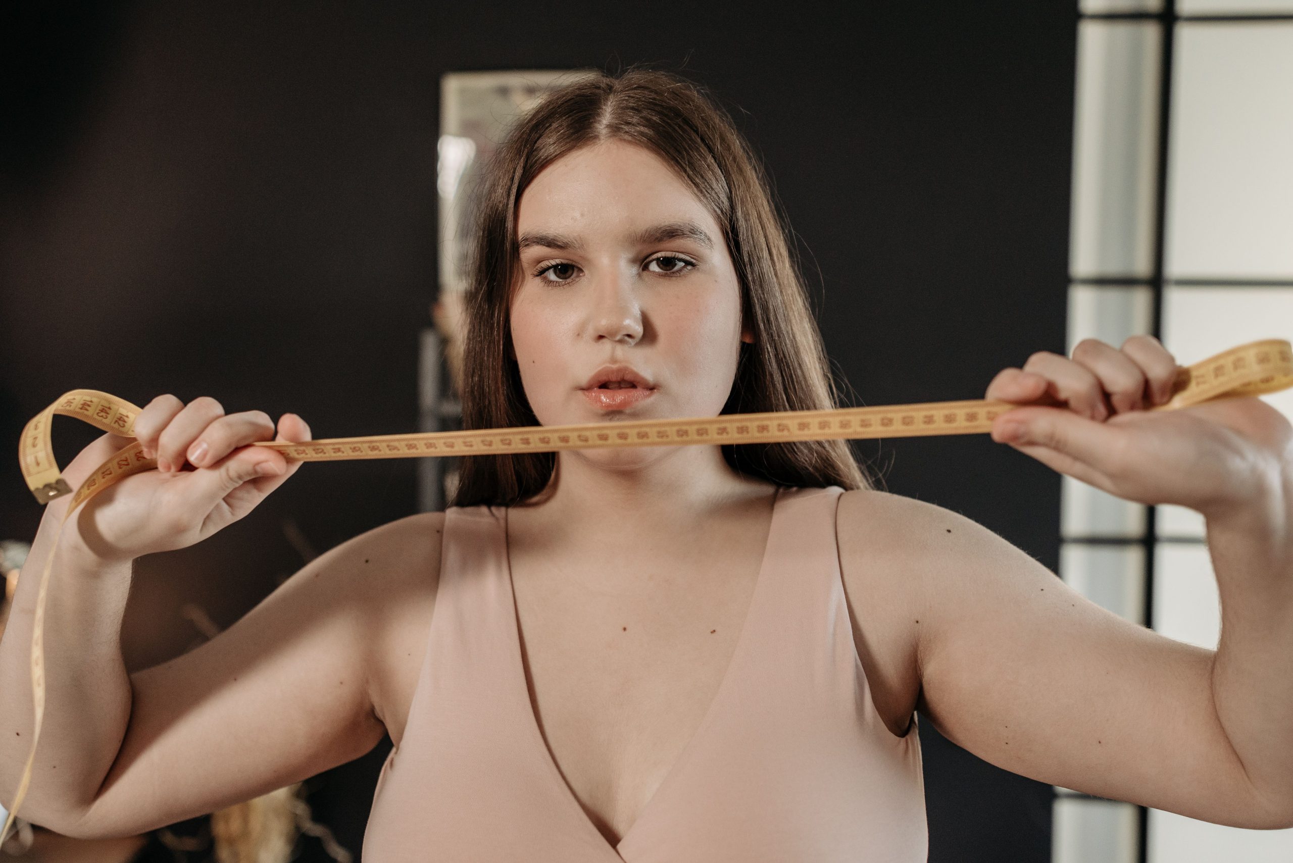 Portrait d'une femme confiante tenant un mètre ruban, symbolisant l'auto-soin et la positivité corporelle.