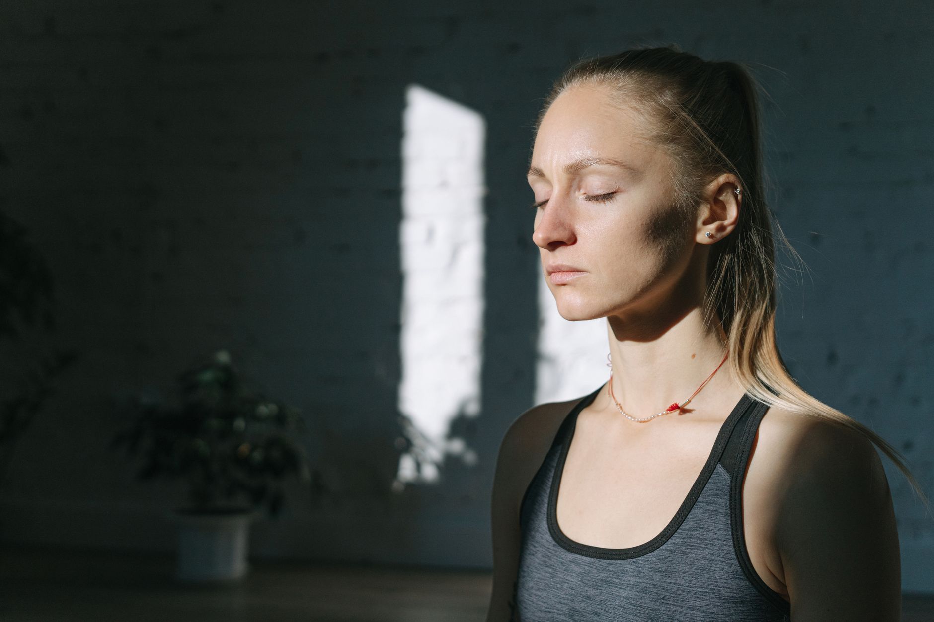 Femme qui médite paisiblement les yeux fermés en intérieur