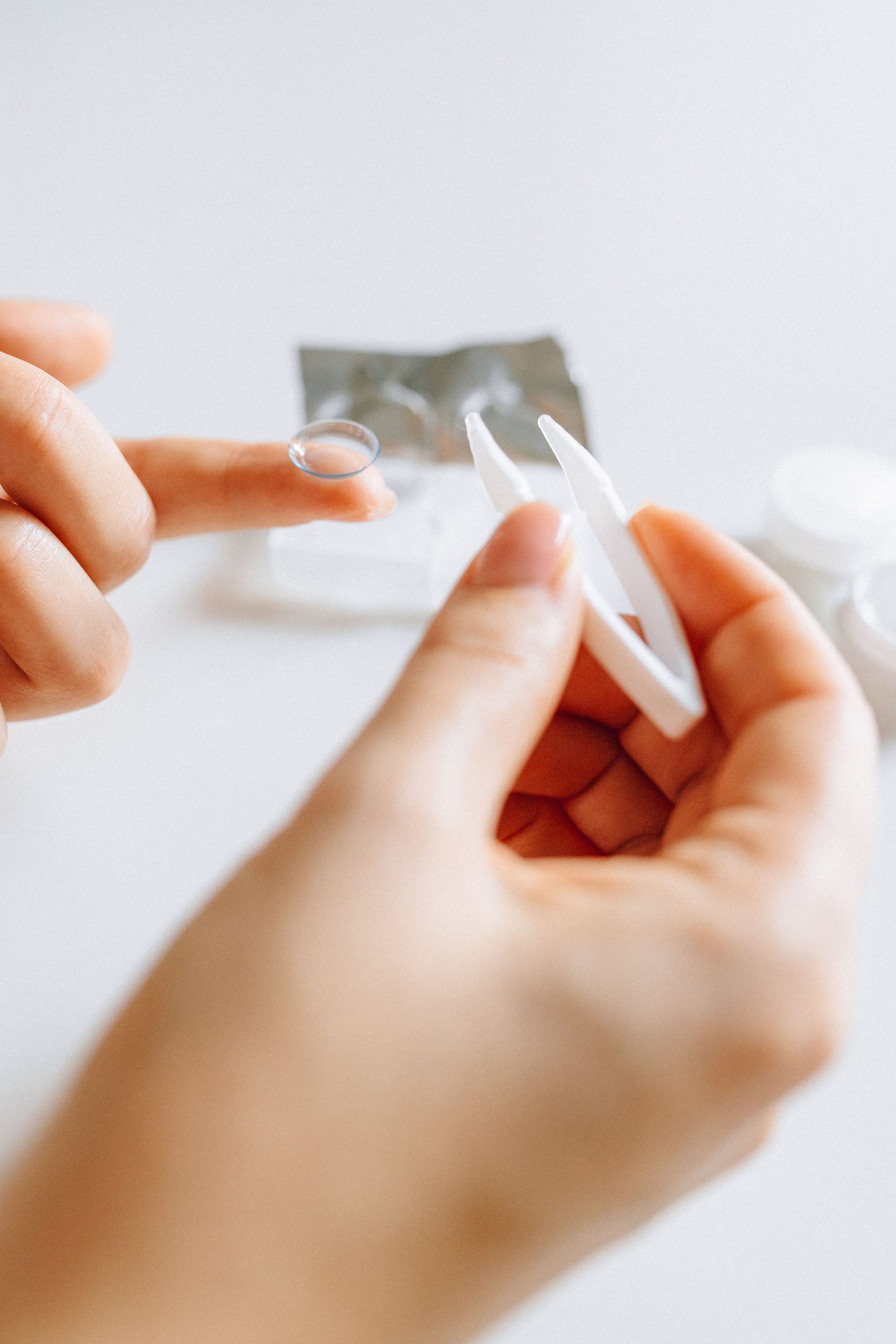 Hands carefully holding a contact lens and case, reflecting daily eye care routine. Des mains tenant soigneusement une lentille de contact et son étui, reflétant la routine quotidienne de soin des yeux.