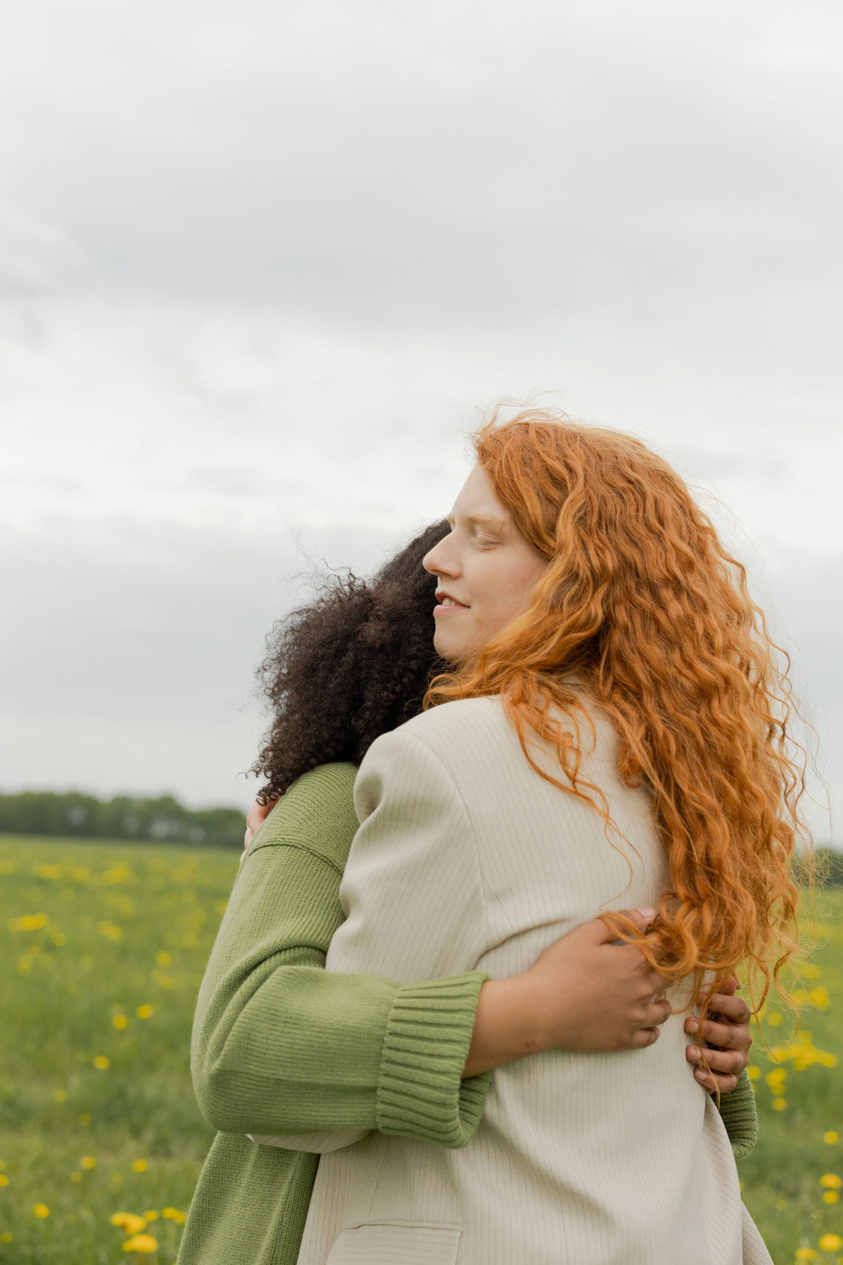 Two women embracing outdoors, showcasing diversity and friendship. Deux femmes s'embrassant en plein air, mettant en avant la diversité et l'amitié.
